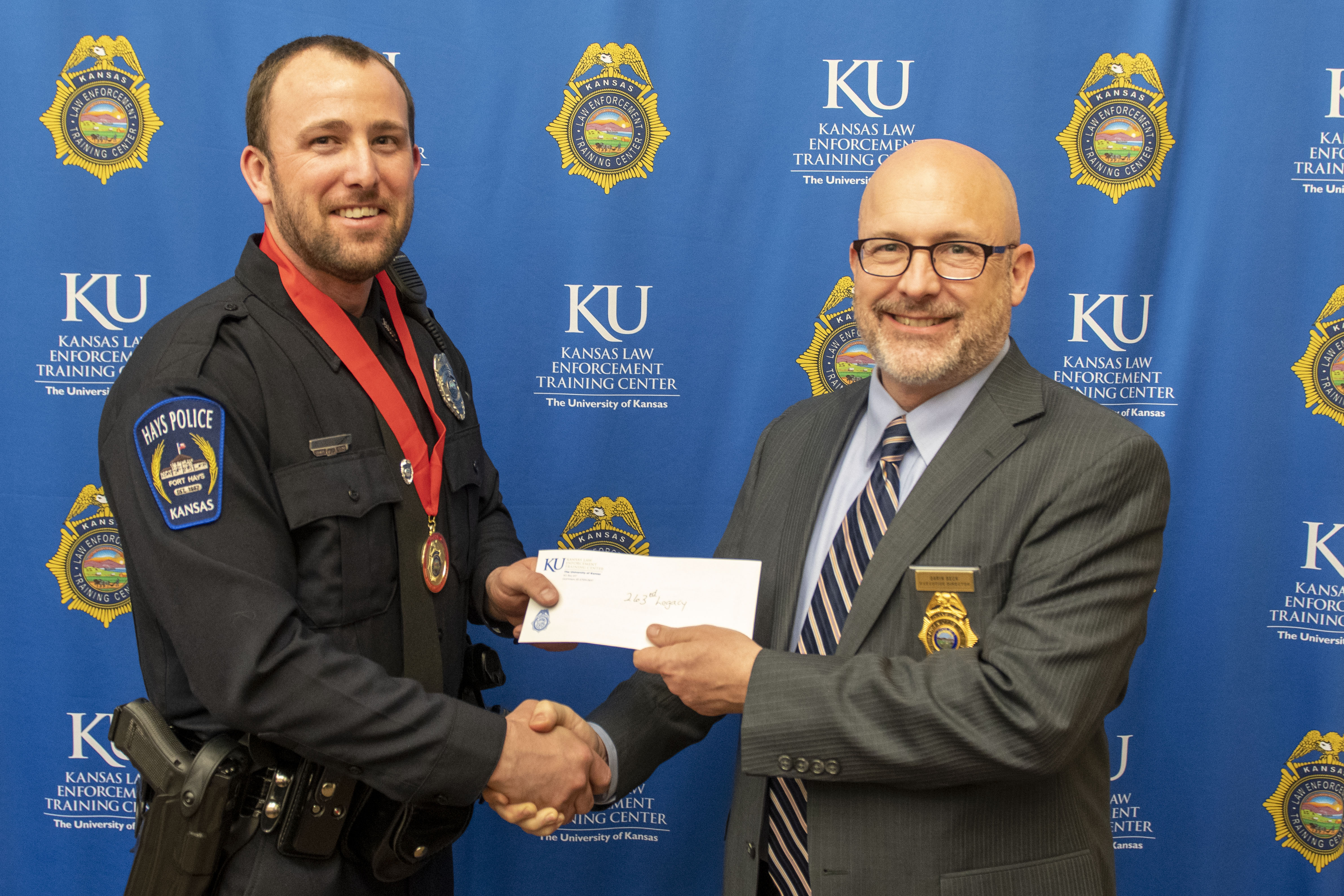 Class president Derrick Crisenbery holds the class donation with KLETC Executive Director Darin Beck